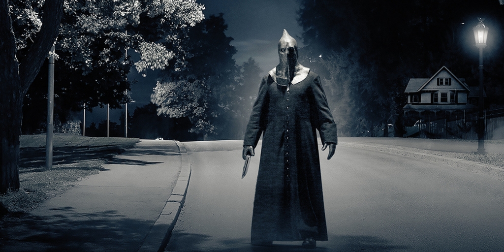 The Executioner stands next to a streetlight in the dead of night.